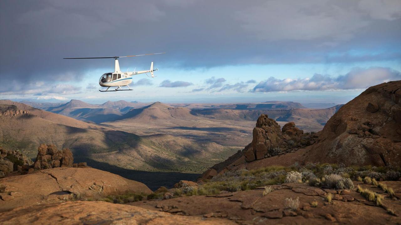 โรงแรมดรอสท์ดี กราฟฟ์-เรเน็ต ภายนอก รูปภาพ A Robinson R44 helicopter flying over the Namib Desert